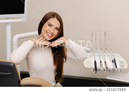 Woman is happy with results for oral hygiene and teeth whitening at dentist. Patient is smiling at the camera after tooth cleaning Woman is happy with results for oral hygiene and teeth whitening at dentist. Patient is smiling at the camera after tooth cleaning 121017889