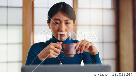 Laptop, tea or Asian woman in home office reading for remote work, research or website. Coffee, author or creative freelancer drinking beverage for campaign, editing or publishing review in Japan 121018244