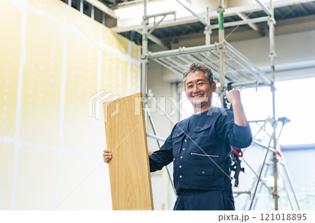 工事現場で材木を持ってガッツポーズする大工 工事現場で材木を持ってガッツポーズする大工 121018895