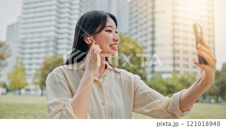 Happy, asian woman and video call with earphones in city for communication, conversation or chat. Japan, female person or talking with mobile smartphone for virtual discussion or app in an urban town Happy, asian woman and video call with earphones in city for communication, conversation or chat. Japan, female person or talking with mobile smartphone for virtual discussion or app in an urban town 121018948