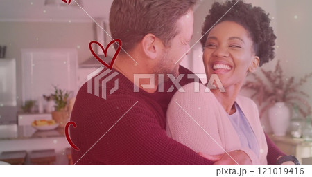 Image of hearts and light spots over diverse couple embracing in kitchen Image of hearts and light spots over diverse couple embracing in kitchen 121019416