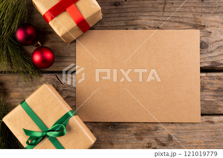 Christmas gifts and decorations with brown card and copy space on wooden background 121019779