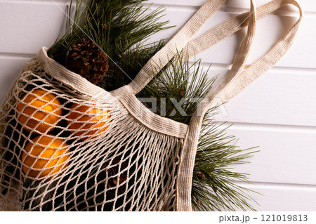 Net bag with chrsitmas fir tree branches and oranges, copy space on white background 121019813
