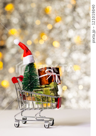 Vertical image of shopping trolley with gifts and christmas fairy lights with copy space background 121019840