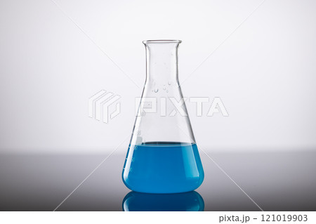 Close up of laboratory beaker with blue liquid and copy space on grey background 121019903