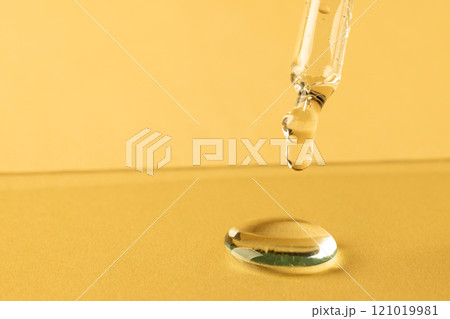 Close up of pipette with drop and copy space on yellow background 121019981