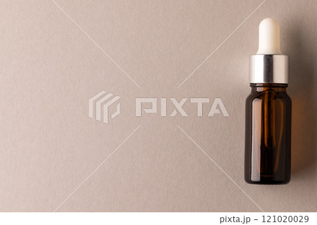 Brown glass bottle with pipette with copy space on brown background 121020029