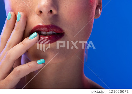 Caucasian woman wearing red lipstick and blue nail polish on blue background Caucasian woman wearing red lipstick and blue nail polish on blue background 121020071