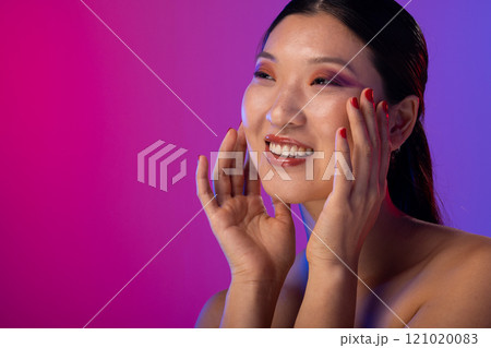 Asian woman wearing purple eye shadow and red nail polish on purple background, copy space 121020083