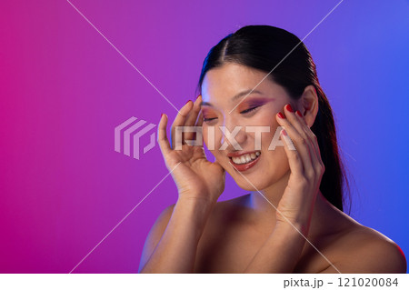 Asian woman wearing purple eye shadow and red nail polish on purple background, copy space 121020084