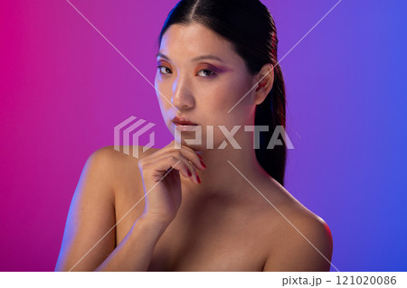 Portrait of asian woman wearing purple eye shadow and red nail polish on purple background Portrait of asian woman wearing purple eye shadow and red nail polish on purple background 121020086