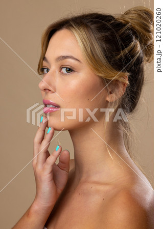 Portrait of caucasian woman wearing natural makeup and blue nail polish on beige background 121020260