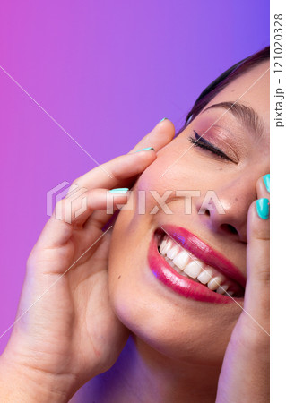 Caucasian woman wearing pink lipstick and blue nail polish on purple background, copy space 121020328