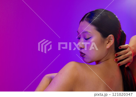 Asian woman wearing blue eyeliner and red nail polish on purple background, copy space Asian woman wearing blue eyeliner and red nail polish on purple background, copy space 121020347