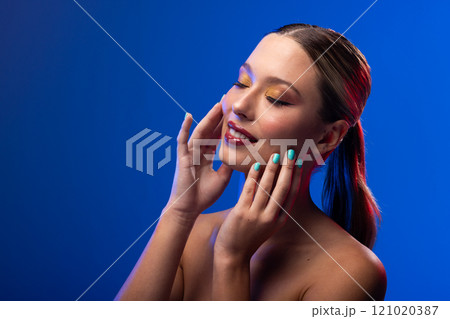 Caucasian woman wearing red lipstick and blue nail polish on blue background, copy space 121020387