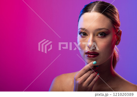 Portrait of caucasian woman wearing blue nail polish on purple background, copy space 121020389