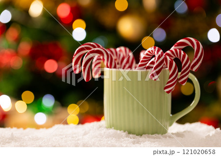 Mug with candy canes and christmas tree with fairy lights and copy space 121020658