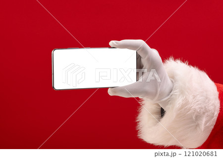 Santa claus holding smattphone with copy space on red background Santa claus holding smattphone with copy space on red background 121020681