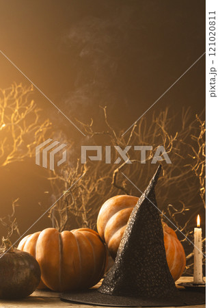 Vertical image of pumpkins and witch hat and burning candle with copy space on orange background Vertical image of pumpkins and witch hat and burning candle with copy space on orange background 121020811