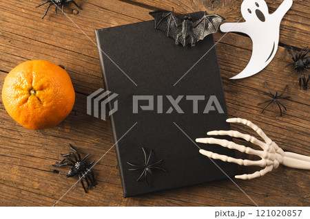 Halloween decorations and skeleton hand on notebook with copy space on brown background Halloween decorations and skeleton hand on notebook with copy space on brown background 121020857