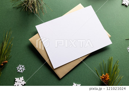 Christmas decorations with white card and copy space on green background Christmas decorations with white card and copy space on green background 121021024