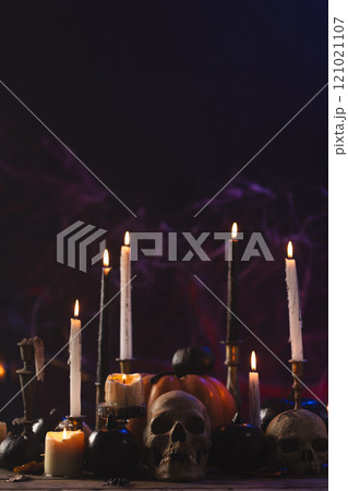 Vertical image of pumpkins, skulls and candles with copy space on purple background 121021107