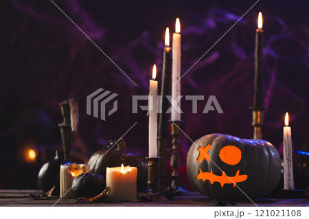 Carved pumpkins and burning candles on purple background 121021108
