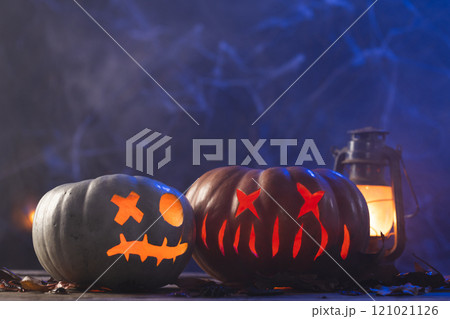 Carved pumpkins and lantern with copy space on blue background 121021126