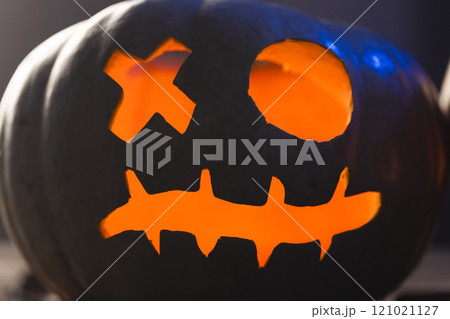 Carved pumpkin face illuminating with orange light on black background Carved pumpkin face illuminating with orange light on black background 121021127