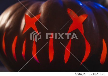 Carved pumpkin face illuminating with red light on black background 121021128