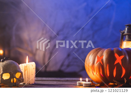 Carved pumpkin, skull and candle with copy space on blue background Carved pumpkin, skull and candle with copy space on blue background 121021129
