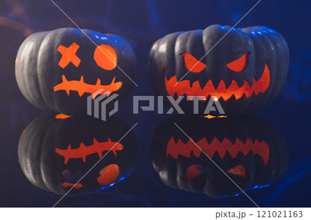 Two black carved pumpkins faces on blue background Two black carved pumpkins faces on blue background 121021163