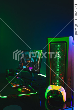 Vertical image of computer with video game accessories with copy space on neon background 121021231