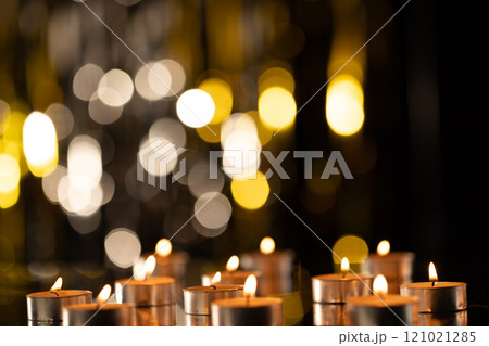 Lit tea candles and bokeh with copy space on black background 121021285