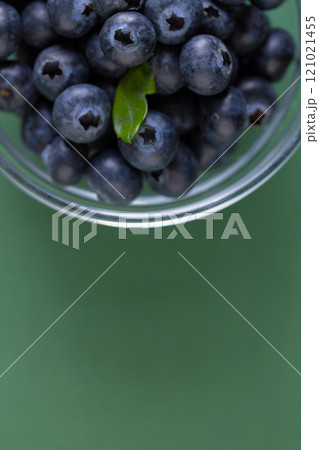 Micro close up of blueberries in glass bowl with copy space on green background Micro close up of blueberries in glass bowl with copy space on green background 121021455