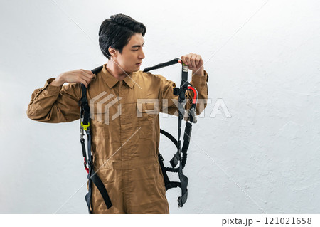 高所作業用フルハーネスを装着する男性作業員 高所作業用フルハーネスを装着する男性作業員 121021658