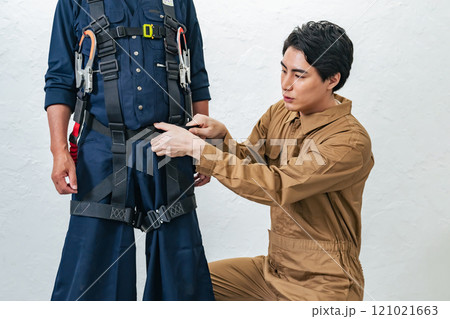 高所作業用フルハーネスの装着方法を教える作業員 高所作業用フルハーネスの装着方法を教える作業員 121021663