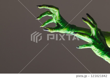 Green monster hands with black nails reaching on grey background 121021842