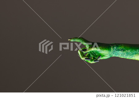 Green monster hand with black nails pointing with finger on grey background 121021851