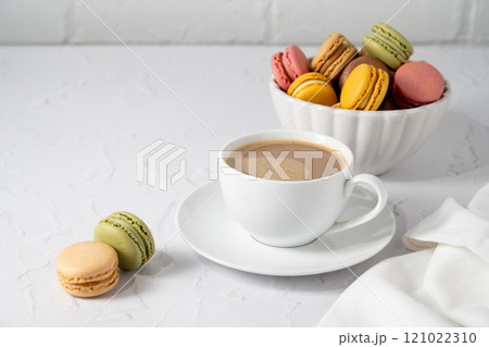 Macarons cookies with cup of coffee, stack of french macarons in a plate. Sweet dessert 121022310