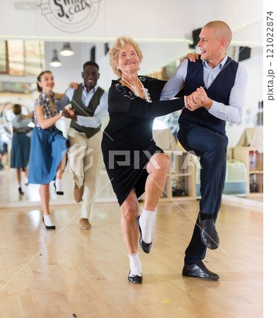 Senior woman and younger man dancing swing in studio Senior woman and younger man dancing swing in studio 121022874