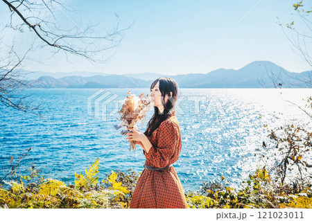 湖でドライフラワーを持って立っている赤いワンピースの女性 湖でドライフラワーを持って立っている赤いワンピースの女性 121023011