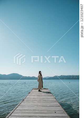 青空のもと湖の辺りに立つ若い女性 青空のもと湖の辺りに立つ若い女性 121023407