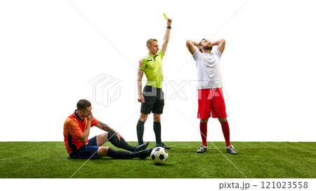 Referee showing yellow card to shocked man, while opponent player sitting on floor with outstretched injured leg, isolated on white background Referee showing yellow card to shocked man, while opponent player sitting on floor with outstretched injured leg, isolated on white background 121023558