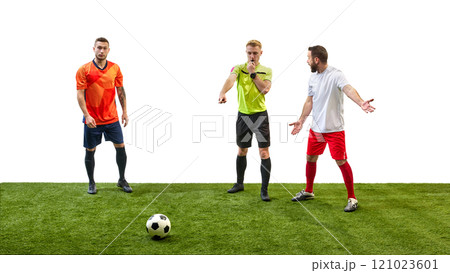 Soccer referee blowing a whistle and making gesture to signal foul while player prepares to take penalty, highlighting rule enforcement in game. 121023601
