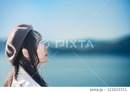 青空をバックにしたベレー帽をかぶりトレンチコートを着た若い女性 青空をバックにしたベレー帽をかぶりトレンチコートを着た若い女性 121023721