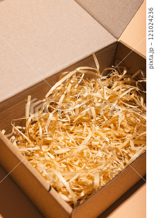 Vertical image of open box with straw lining and copy space over cream background Vertical image of open box with straw lining and copy space over cream background 121024236