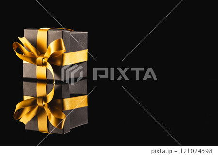 Black gift box with ribbon and copy space over black background Black gift box with ribbon and copy space over black background 121024398