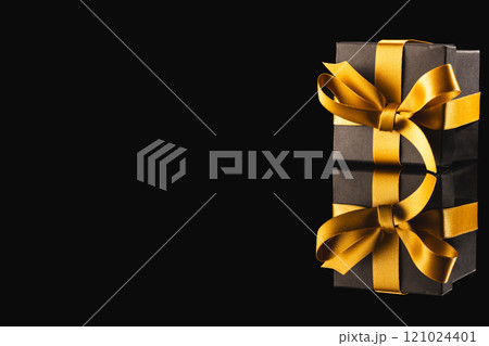 Black gift box with ribbon and copy space over black background 121024401