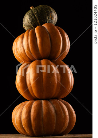 Vertical image of orange and green pumpkins stacked up with copy space on black background Vertical image of orange and green pumpkins stacked up with copy space on black background 121024405